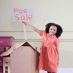 girl holding up a for sale sign