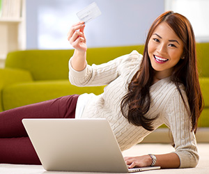 woman on computer holding up credit card