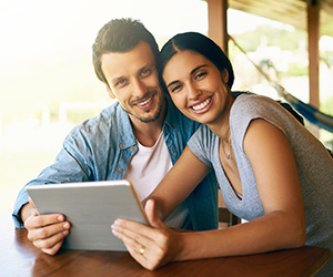 woman and man holding tablet smiling for camera