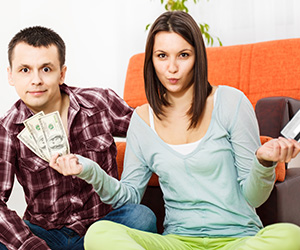 woman and man holding up cash in one hand and credit card in another